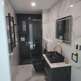 Bathroom in the same flat, with a level-access shower and brass taps