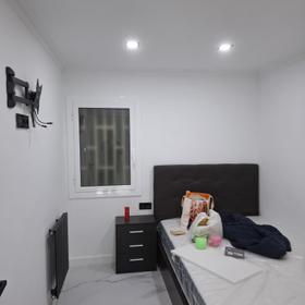 Bedroom with a marble-effect porcelain floor and a dark upholstered headboard