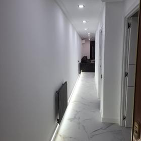 Corridor with an LED strip at skirting level and white lacquered doors