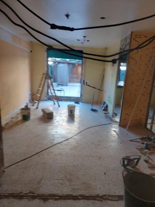 The same living room during the strip-out: bare partitions, temporary wiring and no floor finish