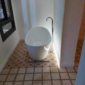 Bathroom in the same flat, with a freestanding bath on the original hydraulic tile