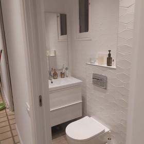 Third bathroom in the same flat, with textured white tiling, a wall-hung WC and a white vanity with an integrated basin