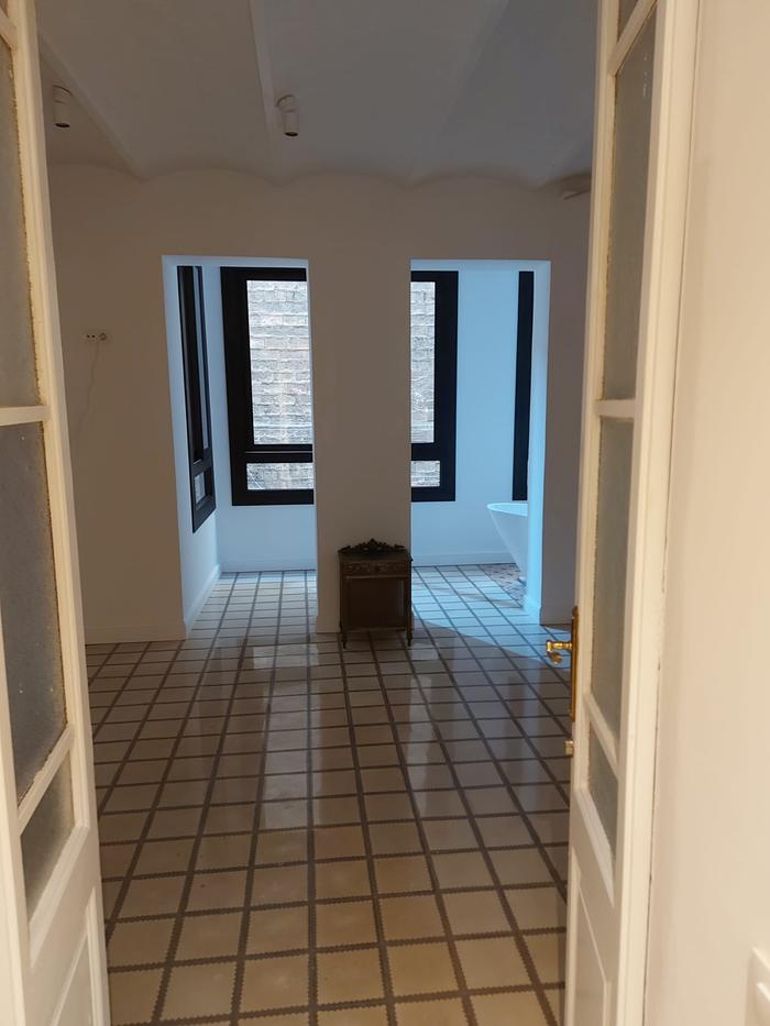 Living room in a period building with the original hydraulic tile floor, black-framed windows and double-leaf doors