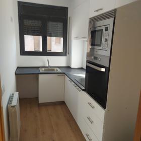 Kitchen in the same flat, narrow and single-run, with an oven and microwave column