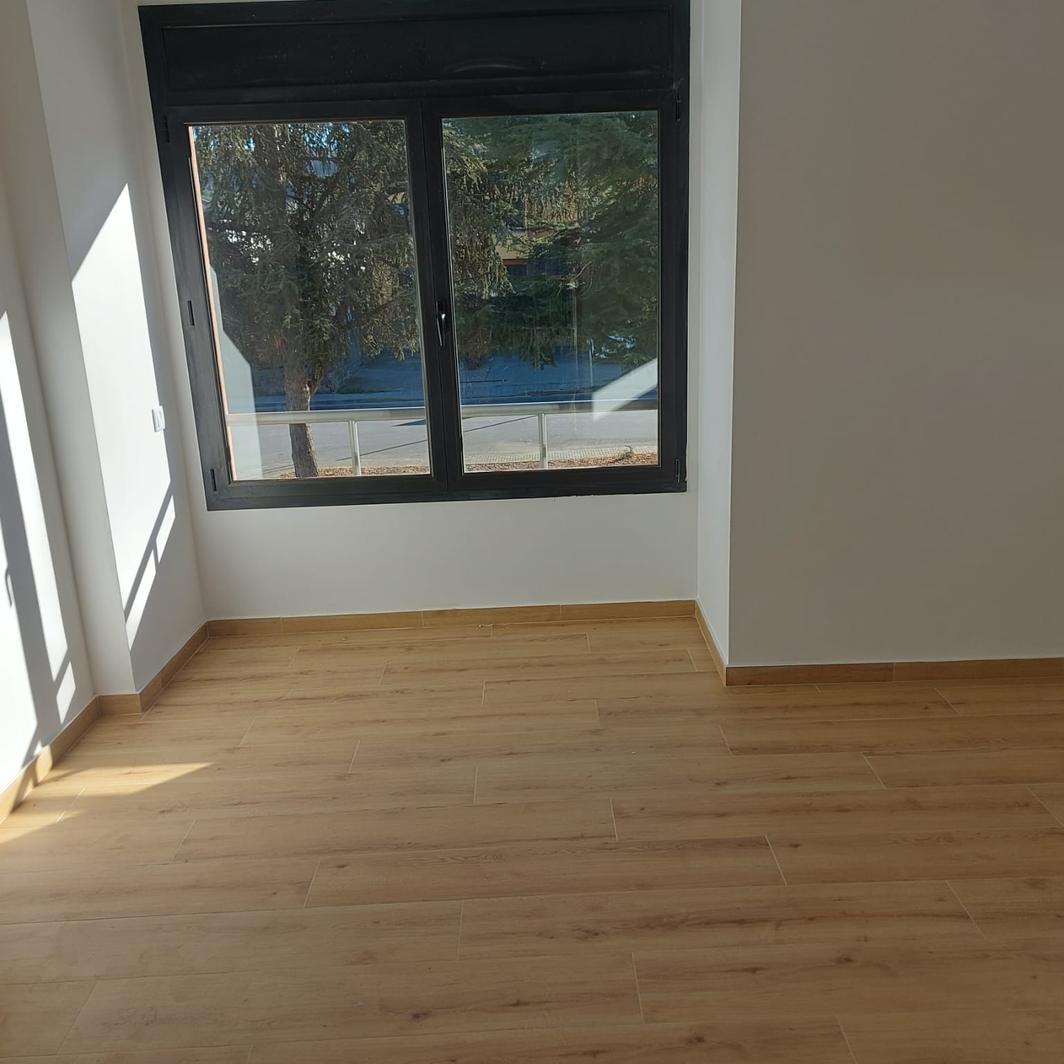 Renovated room with a wood floor, white walls and a black aluminium window